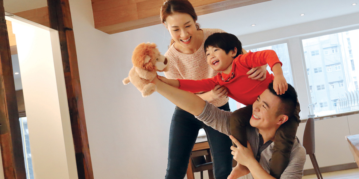 A smiling mother and father playing with their young son at home