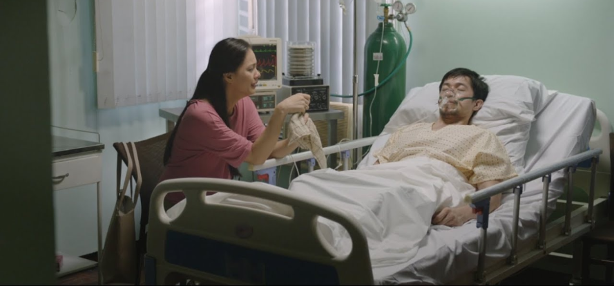 A woman caring for a family member in a hospital bed