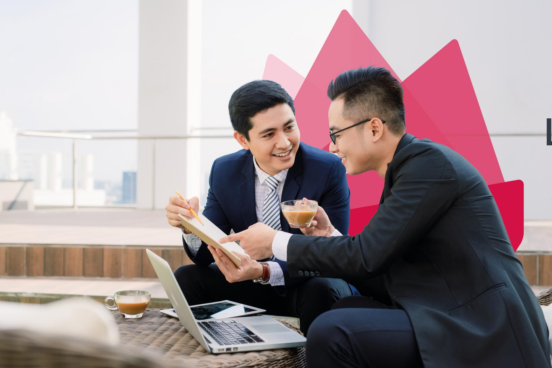 Two financial advisors reviewing notes over coffee